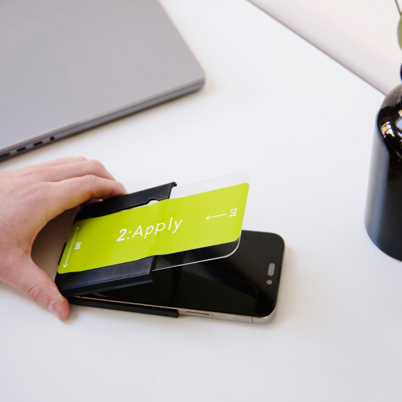 Hand applying a screen protector to a smartphone by a easy applicator.